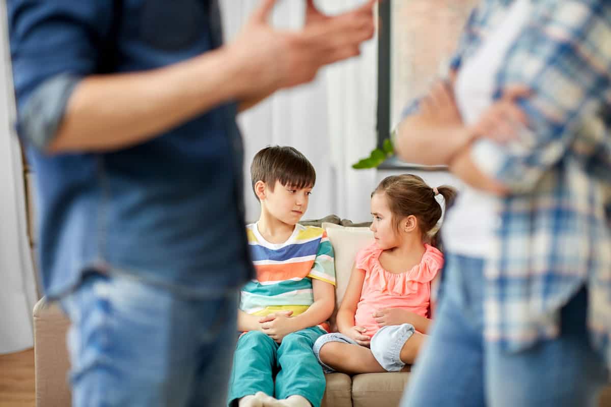 2 children sitting on a couch while divorced parents talk about mediation.